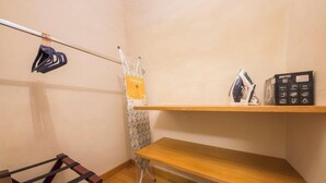 Een hoek van een kamer met een houten plank, een kledingrek en een metalen ladder.