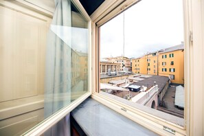 Ein Fenster mit Blick auf eine Stadtlandschaft, darunter Gebäude und eine Brücke.