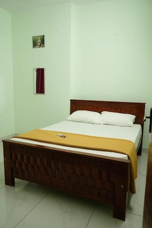A single bed with a wooden headboard, a white mattress, and a yellow bedspread.