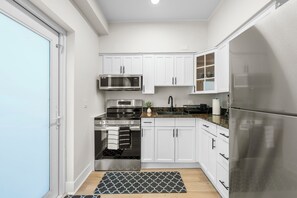 Eine moderne Küche mit weißen Schränken, Edelstahlgeräten und einem schwarz-weißen Teppich.