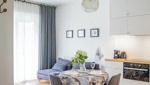 A modern kitchen with white cabinets, a dining table with chairs, and a hanging light fixture. - Rakowicka Apt - Main Station, Old Town nearby - by Rentujemy (Kraków)