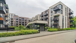 A modern apartment building with multiple balconies, a covered entrance, and a paved walkway. - Rakowicka Apt - Main Station, Old Town nearby - by Rentujemy (Kraków)