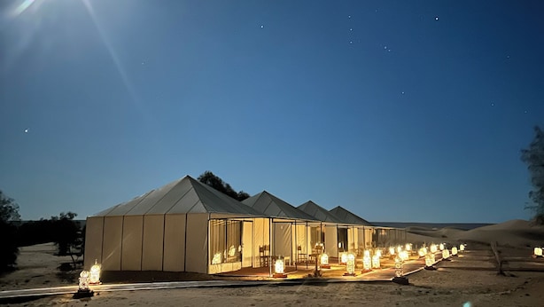 Un grand bâtiment moderne, conçu comme une tente et comprenant plusieurs pièces, situé dans un environnement désertique.