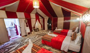 A tent-style room with multiple beds, a chandelier, and a patterned carpet. - nomadcampmerzouga (Merzouga)