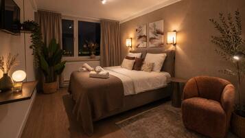 Un dormitorio moderno con cama, mesitas de noche, una silla y una ventana con cortinas.
