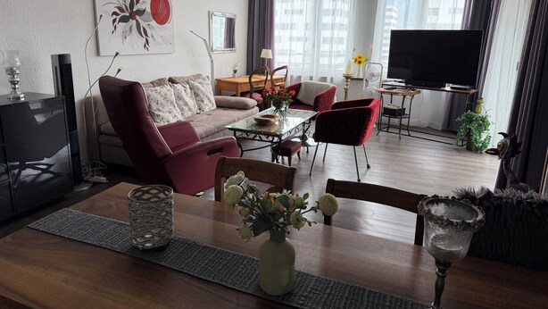 A modern living room with a sofa, chairs, a dining table, a TV, and a large window with curtains. - Panorama Ideal, 2.5-room vacation rental in Locarno (Locarno)