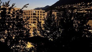 A multi-story building with a modern architectural design, surrounded by trees and a mountain in the background. - Panorama Ideal, 2.5-room vacation rental in Locarno (Locarno)