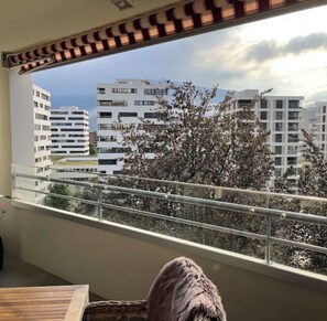 Ein Balkon mit Blick auf moderne Gebäude und einen Baum mit weißen Blüten.