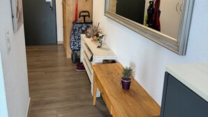 A hallway with a wooden bench, a mirror, a small table with a plant, and a coat rack with clothes. - Panorama Ideal, 2.5-room vacation rental in Locarno (Locarno)