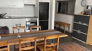 A modern kitchen with white cabinets, a dining table with chairs, a rug, and a clock on the wall. - Panorama Ideal, 2.5-room vacation rental in Locarno (Locarno)
