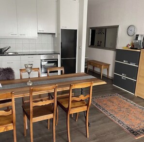 Eine moderne Küche mit weißen Schränken, einem Esstisch mit Stühlen, einem Teppich und einer Uhr an der Wand.