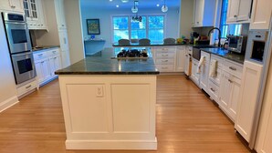 Una cocina moderna con armarios blancos, una isla central y electrodomésticos integrados.