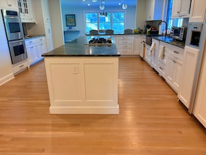 A modern kitchen with white cabinetry, a central island, and built-in appliances.