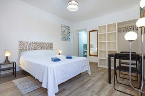 Une chambre à coucher comprenant un lit, des lampes de chevet, un bureau avec des chaises et un miroir.