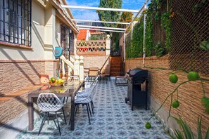 Une terrasse avec une table, des chaises et un barbecue.