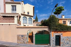 Un bâtiment à la façade en pierre, avec une porte verte et un ciel d’un bleu limpide.