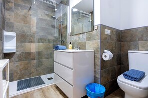Une salle de bain équipée d’une douche, de toilettes, d’un lavabo et d’un miroir.