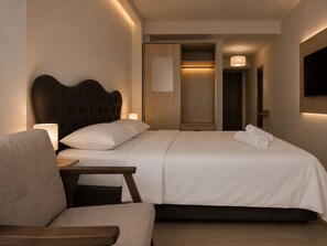 A hotel room with a bed, bedside table, chair, and a TV mounted on the wall. - Kadıkoy Metro Central Apart  (İstanbul)