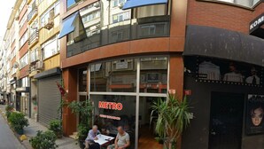 Un edificio con il cartello 'METRO', una vetrina e una zona con posti a sedere all'esterno.