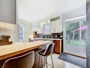 A modern kitchen with a bar area, large windows, and a view of the outdoors. - Charming 4-bedroom cottage with AC in beautiful Québec (Québec)