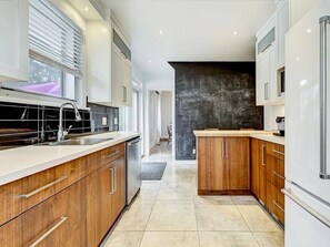 A modern kitchen with wooden cabinets, a stainless steel sink, and a black backsplash. - Charming 4-bedroom cottage with AC in beautiful Québec (Québec)