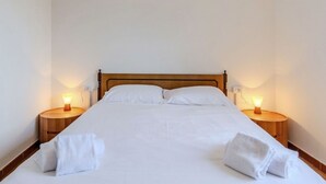 A neatly made bed with white linens and two bedside tables with lamps. - Cosy apartment for 5 guests with WIFI, patio, pets allowed and panoramic view (Peglio)
