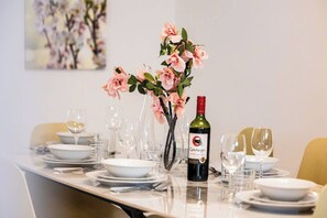 A dining table set with plates, glasses, and a bottle of wine, with a vase of flowers in the center. - Enjoy a stylish 3-bedroom, 3-bathroom maisonette in St Paul’s Bay, located in Triq Il-Parroċċa. With a modern kitchen, bright dining area, air conditioning, and a private backyard, it is ideal for families, couples, and group stays. (St. Paul's Bay)