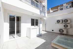 A modern outdoor area with a glass door, a white counter, and multiple air conditioning units. - Enjoy a stylish 3-bedroom, 3-bathroom maisonette in St Paul’s Bay, located in Triq Il-Parroċċa. With a modern kitchen, bright dining area, air conditioning, and a private backyard, it is ideal for families, couples, and group stays. (St. Paul's Bay)