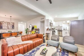 Ein modernes Wohnzimmer mit einer Ledersofa, grauen Sesseln und einem Couchtisch.