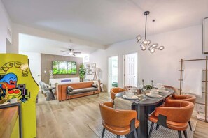 Ein modernes Wohnzimmer mit einer Couch, einem Esstisch für sechs Personen und einem großen Fenster.