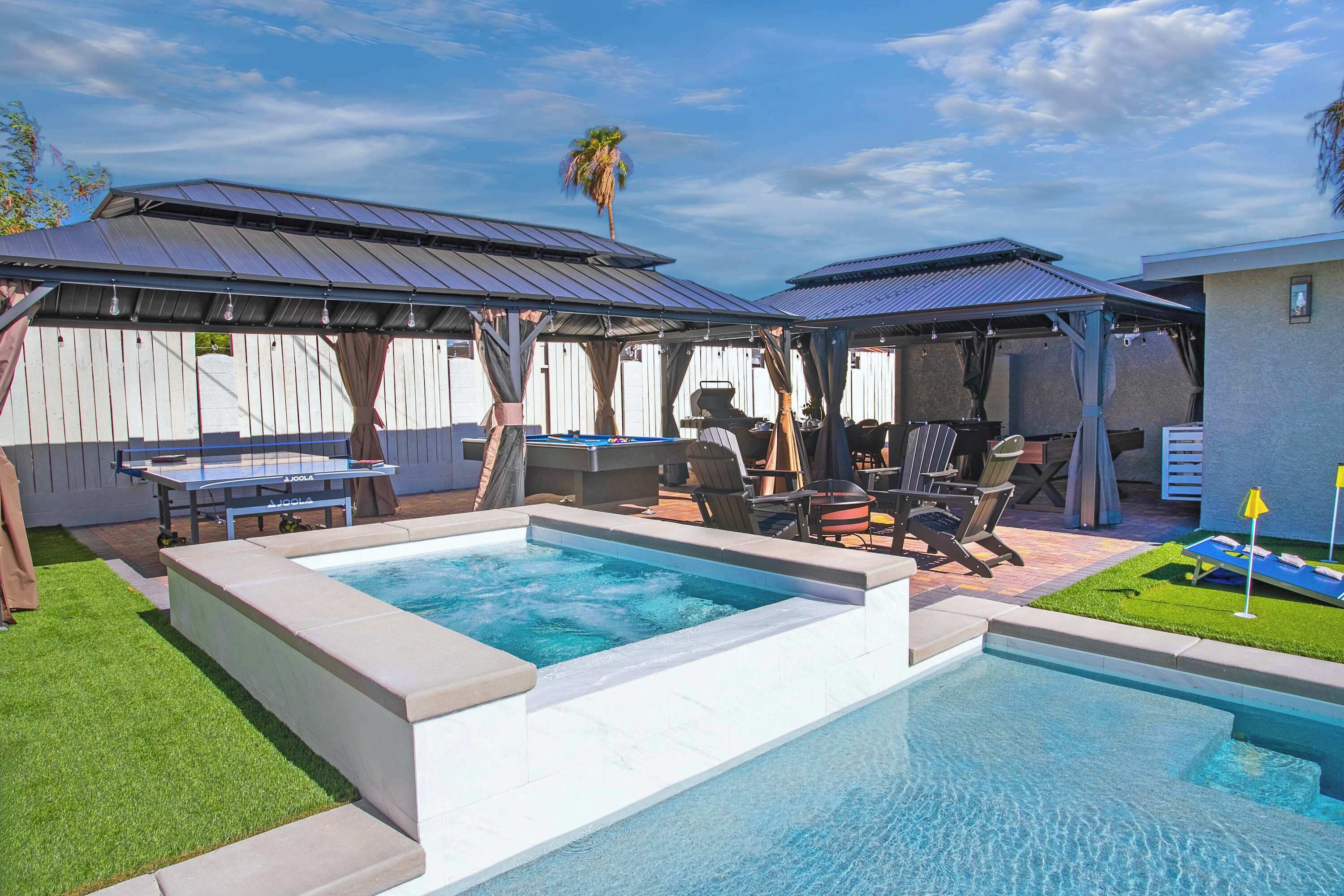 Ein Garten mit Swimmingpool, Gartenmöbeln und einer überdachten Grillgelegenheit.