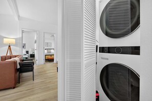 A modern laundry room with two large front-loading washing machines, a wooden floor, and a white interior. - 8BR Power Stay | Space, Comfort & Modern Living! (North Las Vegas)