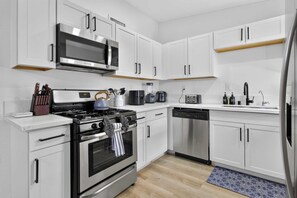 Eine moderne Küche mit weißen Schränken, Edelstahlgeräten und Holzboden.