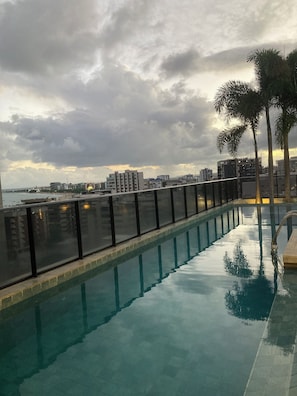 A swimming pool with a view of a cityscape and palm trees. - Time Luxury Stay Rooftop premium with sauna and rooftop pool in Maceió (Maceió)