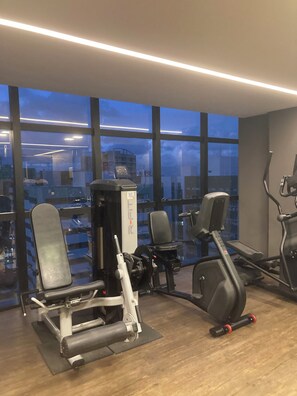 A gym with exercise equipment, large windows, and a view of buildings. - Time Luxury Stay Rooftop premium with sauna and rooftop pool in Maceió (Maceió)