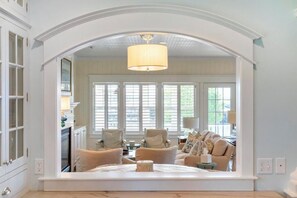 A bedroom with a large mirror, a bed, and a view of the living room through the mirror. - Harbor Cottage: 4  BR, 3.5  BA Cottage in Harbor Springs , Sleeps 12 (Harbor Springs)