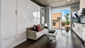 Moderni huoneisto, jossa on sohva, sohvapöytä, ruokailutila ja keittiö.