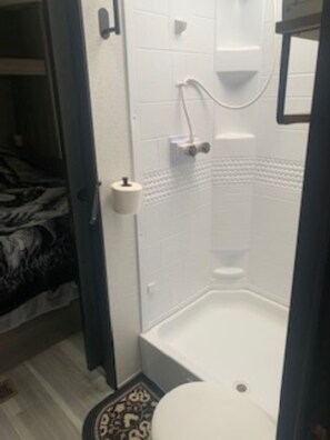 Kylpyhuone, jossa on suihku, wc ja kuviollinen matto.
