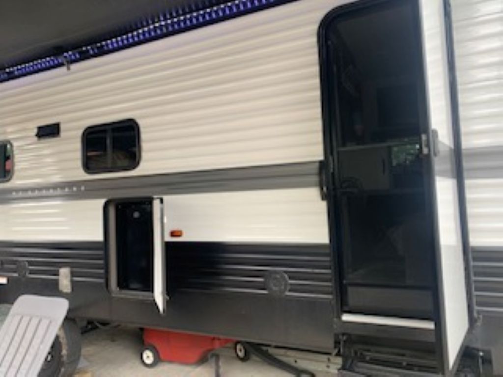 Un camper con una porta scorrevole, un piccolo oblò e un gradino rosso che conduce all'ingresso.