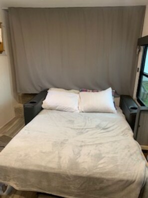 A large bed with a neutral-colored duvet, two bedside tables, and a window with curtains.