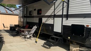 En autocamper med en overdækket terrasse, et bord og stole.