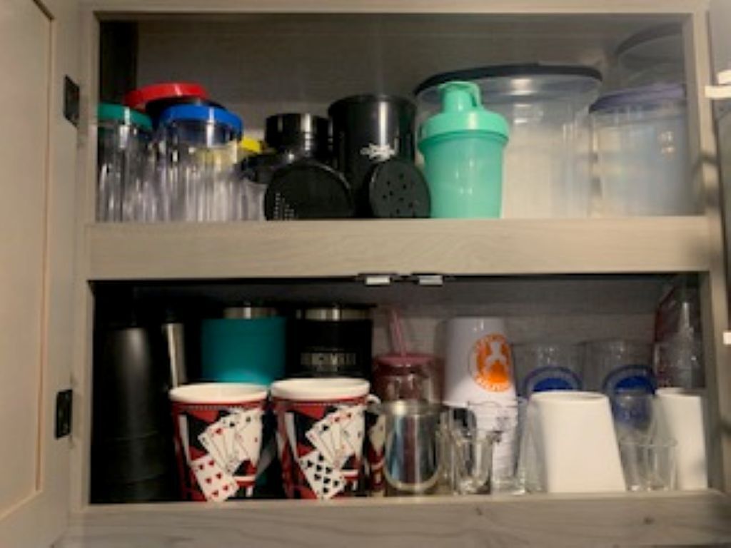 A storage cabinet with various containers and kitchenware.