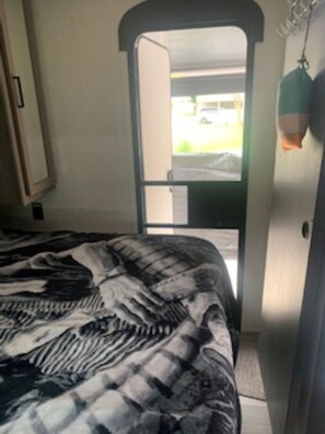 A bedroom with a bed, a door leading outside, and a hanging light fixture.
