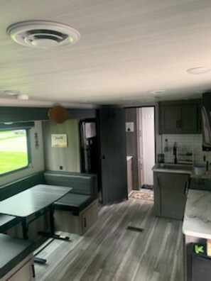 A compact kitchen with a dining area, a window with a view, and a door leading to another room.