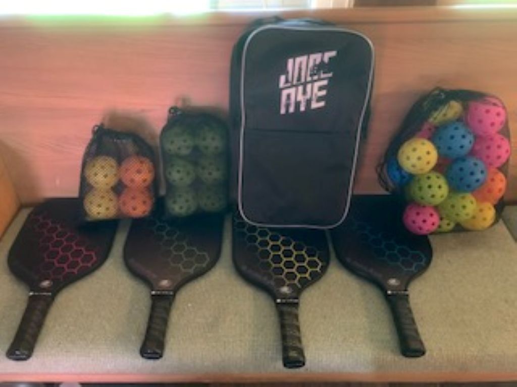 A row of black and colorful paddleboards with a black case labeled 'JACK AYE' in the center.