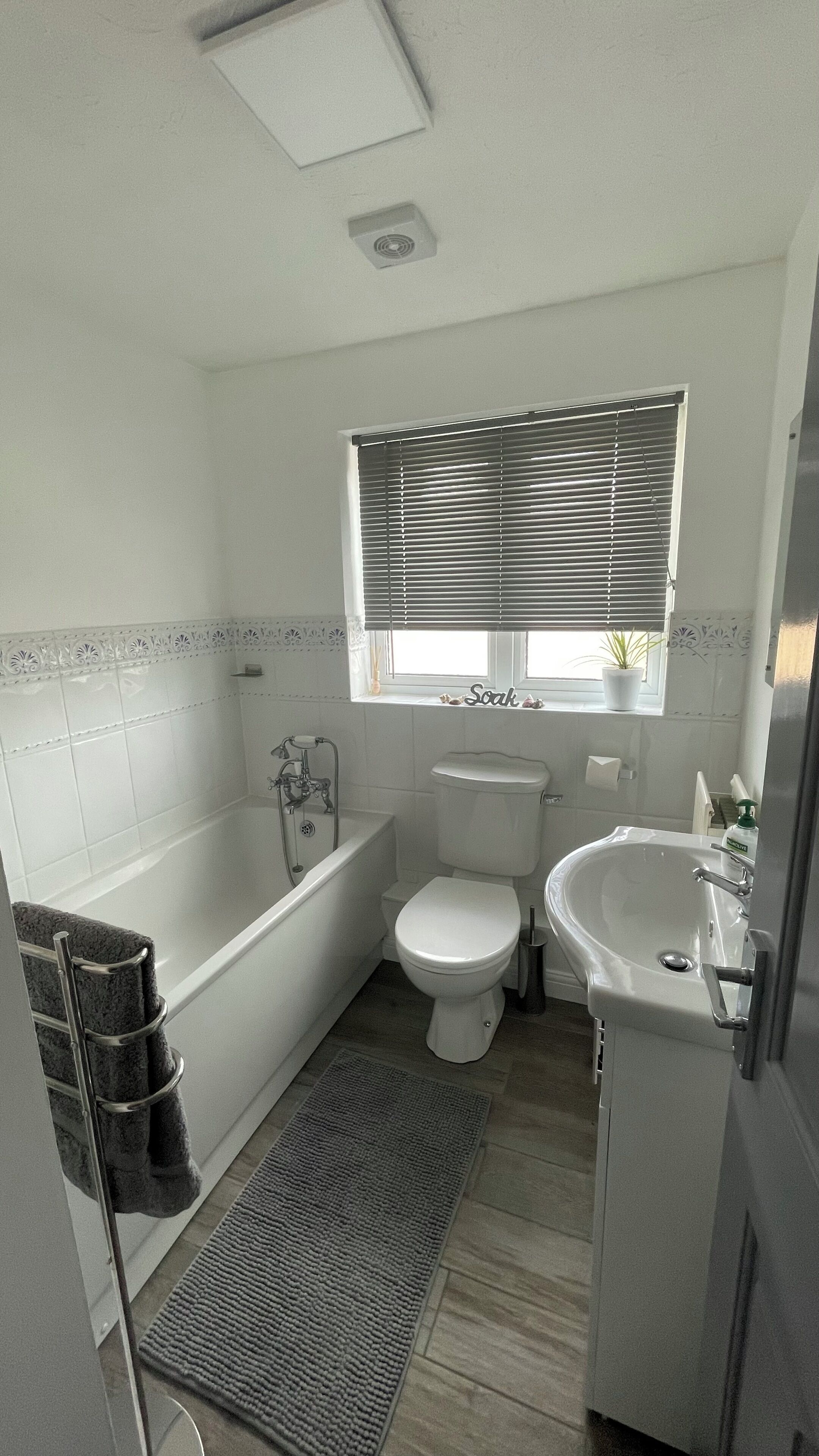 A bathroom with a bathtub, toilet, sink, and a window with blinds.