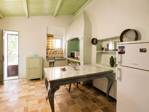 A kitchen with a table, a refrigerator, a sink, and a window with curtains. - Cozy Stay in Chios Near the Beach Private Balcony (Chios)