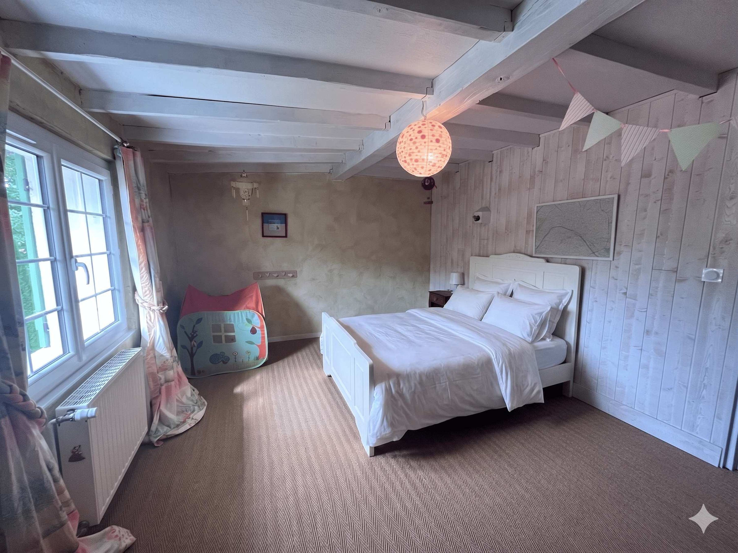 Una camera da letto con un letto, una finestra, un termosifone, un lampadario a parete e un quadro appeso al muro.