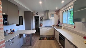 Uma cozinha compacta com forno embutido, micro-ondas e exaustor de aço inoxidável.