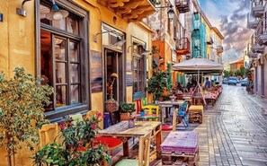Eine enge Straße mit Außenbestuhlung, einem Café und einer Reihe bunter Gebäude.